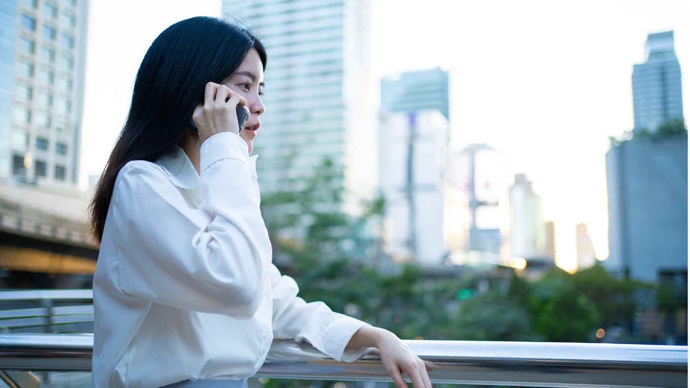 A professional on a phone call with the Bangkok skyline in the background